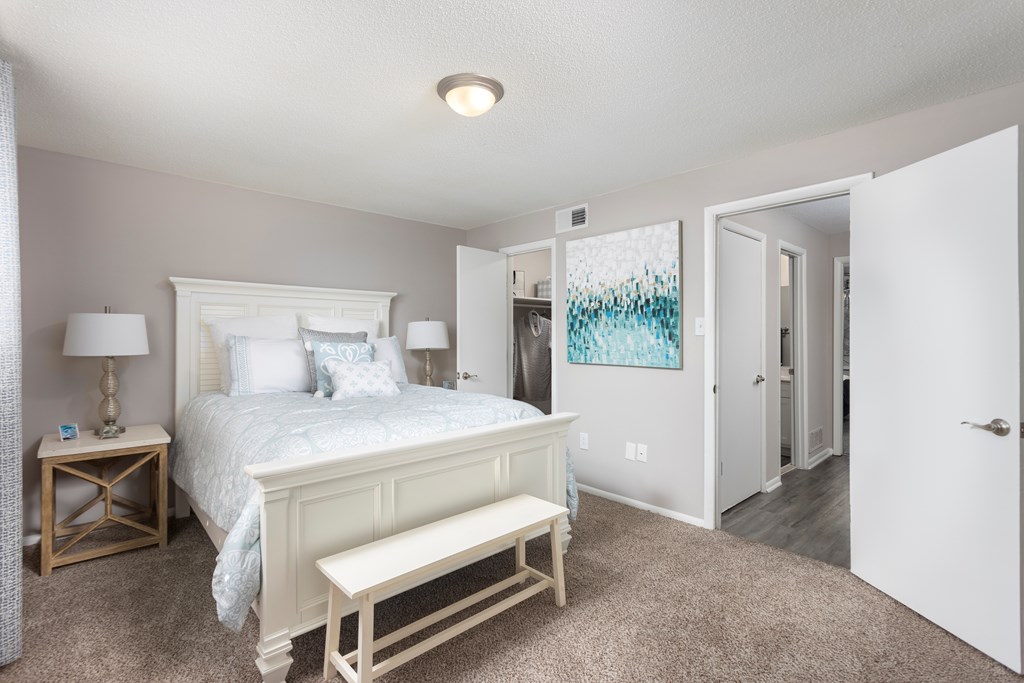 A bedroom with a large bed and a painting on the wall.