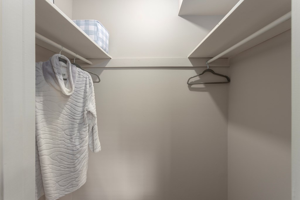 A white towel hangs on a hanger in a white closet.