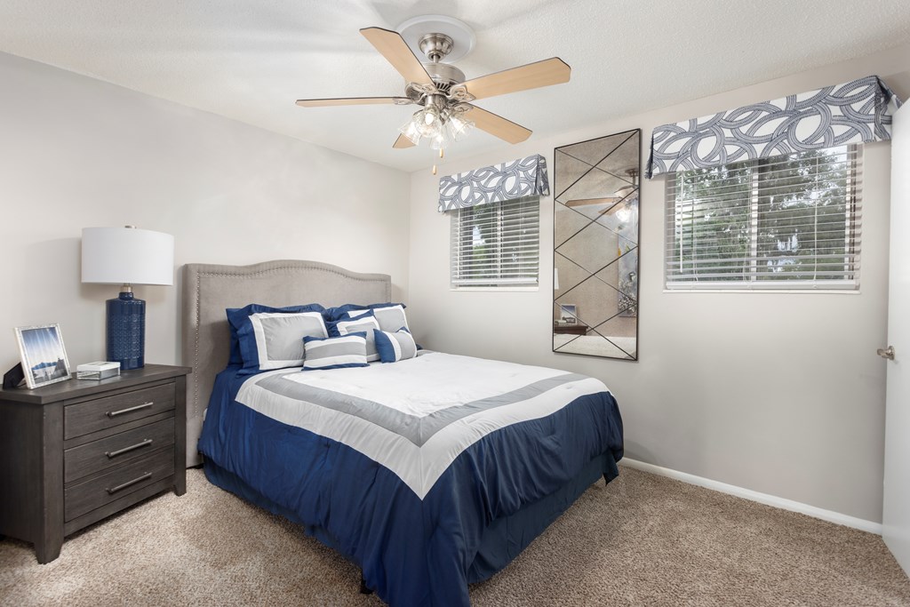 A bedroom with a bed, dresser, and ceiling fan.