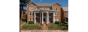 A large red brick building with a central entrance and steps leading up to it.
