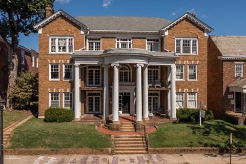 A large red brick building with a central entrance and steps leading up to it.
