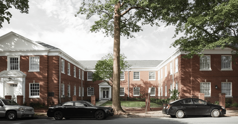 A black car is parked in front of a red brick building.