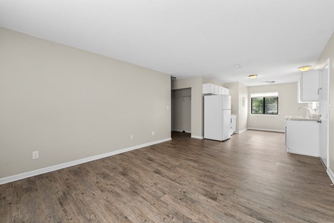A spacious room with wooden flooring and white walls.
