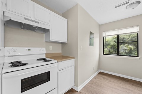 A white stove and oven in a kitchen with a window.