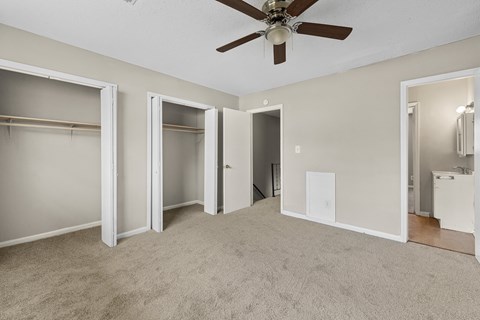 A room with a ceiling fan and carpeted floor.