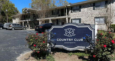 A sign for Country Club Apartments is in front of a building.