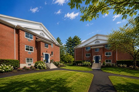 Two brick residential buildings with landscaped grounds at The Miles Apartments, South Hamilton, Massachusetts
