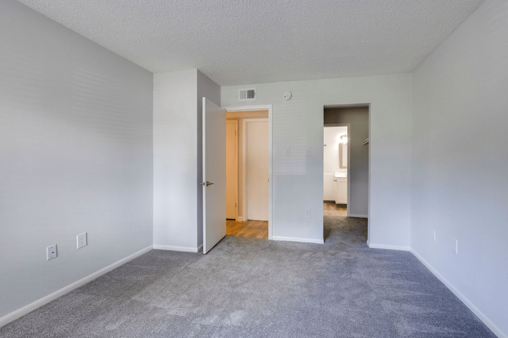 A room with a carpeted floor and a wooden door at Retreat at Savannah Apartments, Savannah