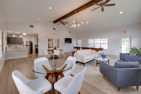 A modern living room with a glass table surrounded by white chairs.