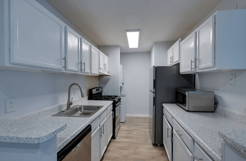 A kitchen with white cabinets and a black refrigerator.