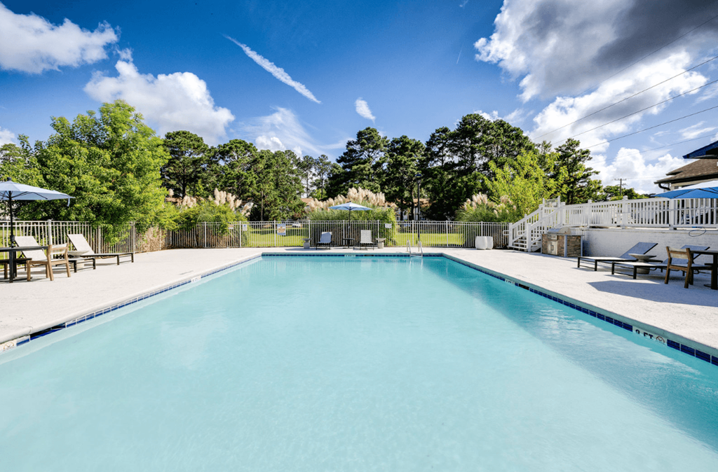 A large swimming pool surrounded by trees and a fence at Retreat at Savannah Apartments, Savannah, Georgia