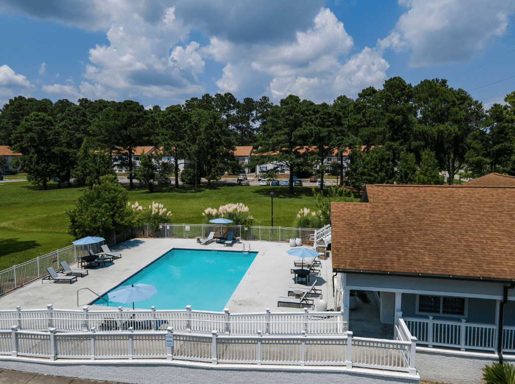 A pool surrounded by a white fence with trees in the background at Retreat at Savannah Apartments, Savannah, Georgia