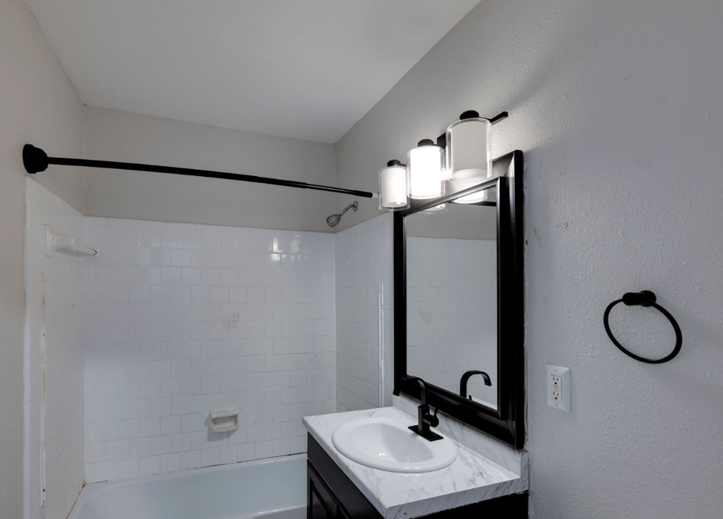 A bathroom with a white sink and a white tiled shower at Savan Pointe Apartments, Savannah 31406
