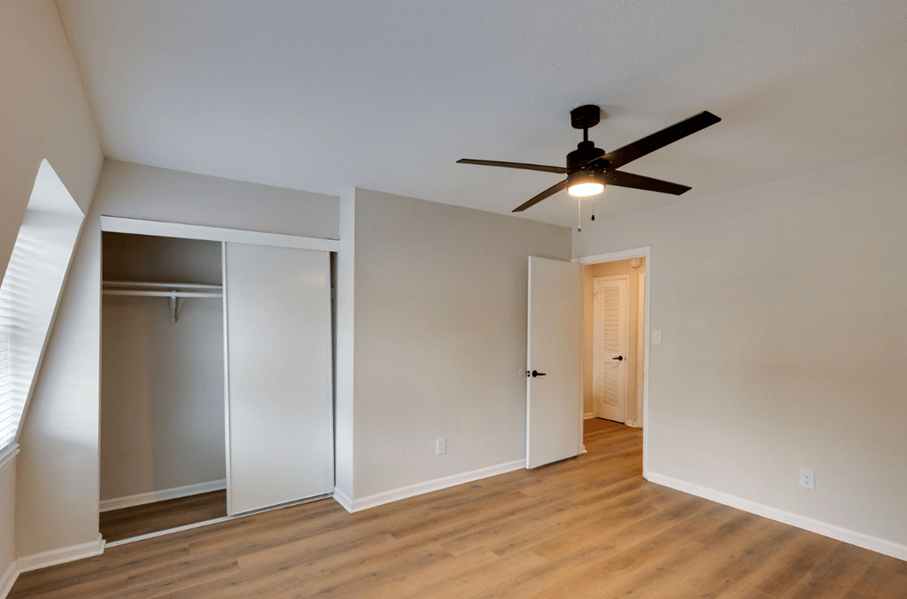 A room with a ceiling fan and wooden floors at Savan Pointe Apartments, Georgia, 31406
