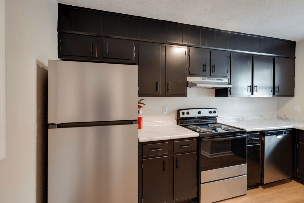 A kitchen with a stainless steel refrigerator and black cabinets at Savan Pointe Apartments, Savannah, Georgia