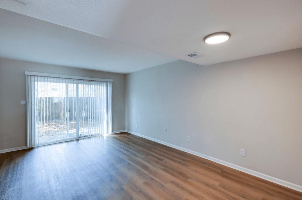 A room with a sliding glass door and wooden flooring at Savan Pointe Apartments, Savannah, GA