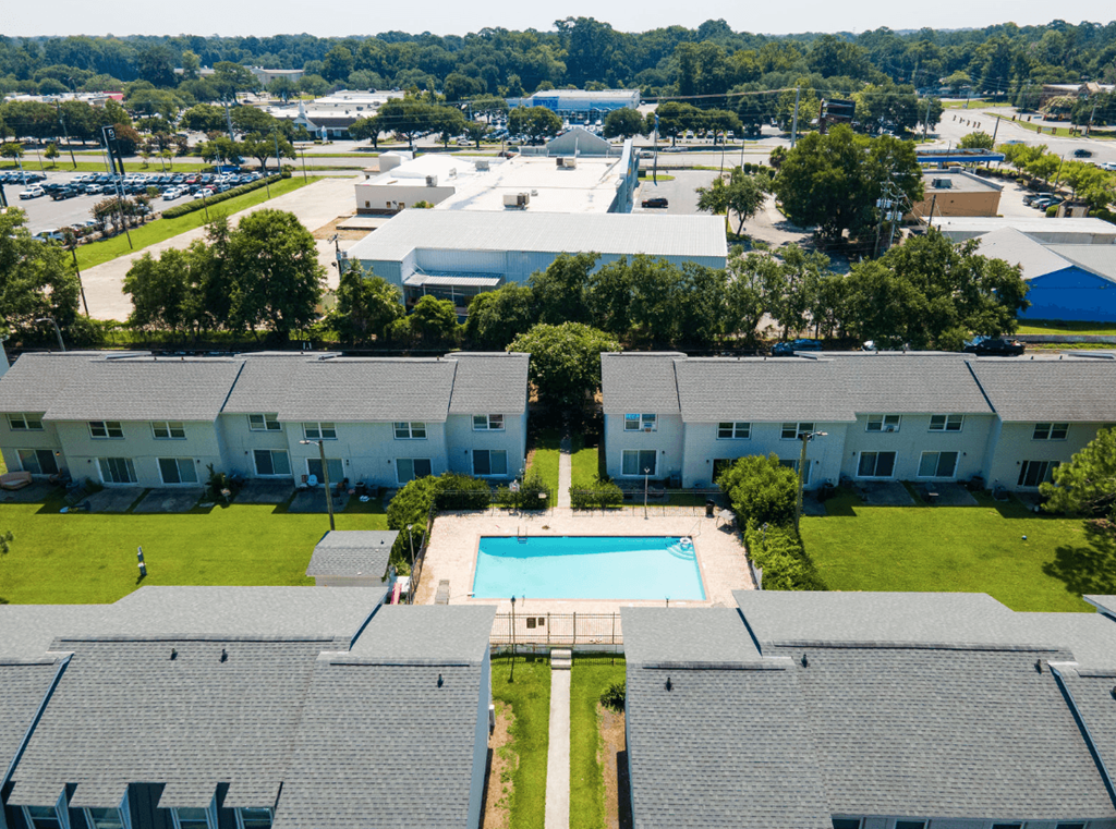 A large white building with a pool in the middle of a grassy area at Savan Pointe Apartments, Georgia, 31406