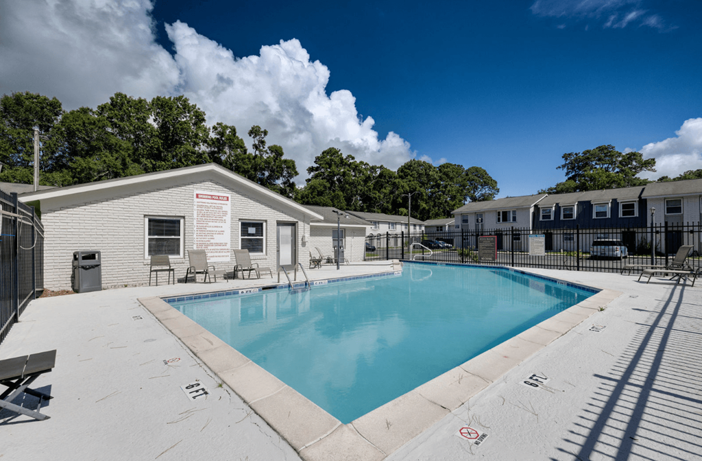 A swimming pool surrounded by a concrete patio and a small building at Savan Pointe Apartments, Savannah, GA, 31406