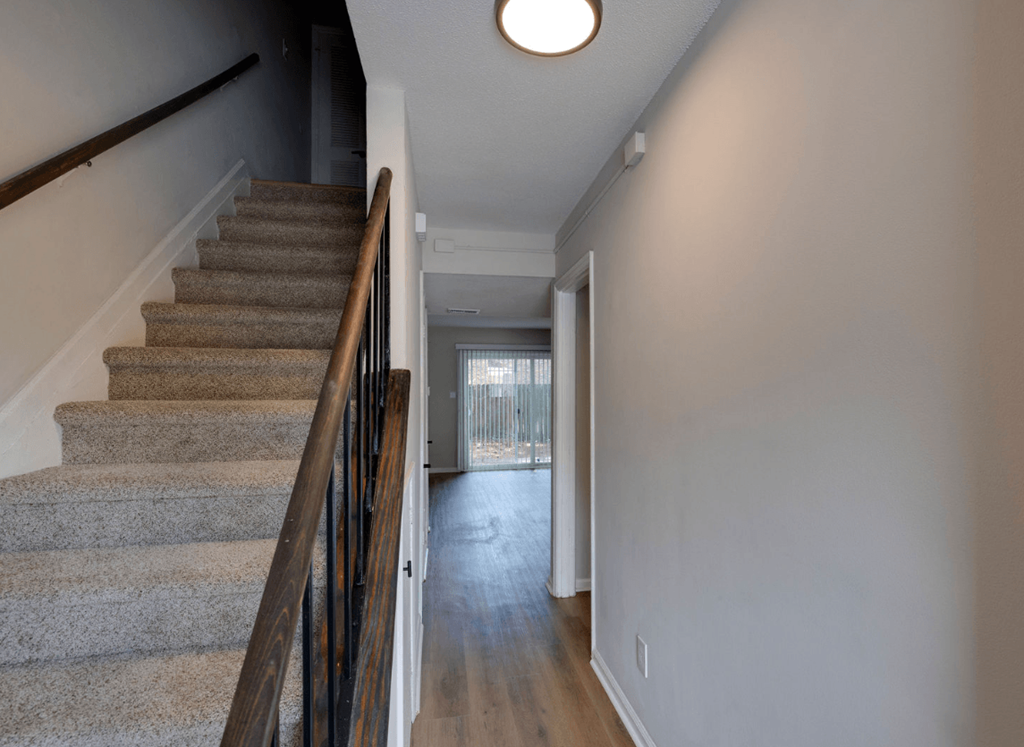 A staircase with a carpeted runner and wooden banister at Savan Pointe Apartments, Georgia