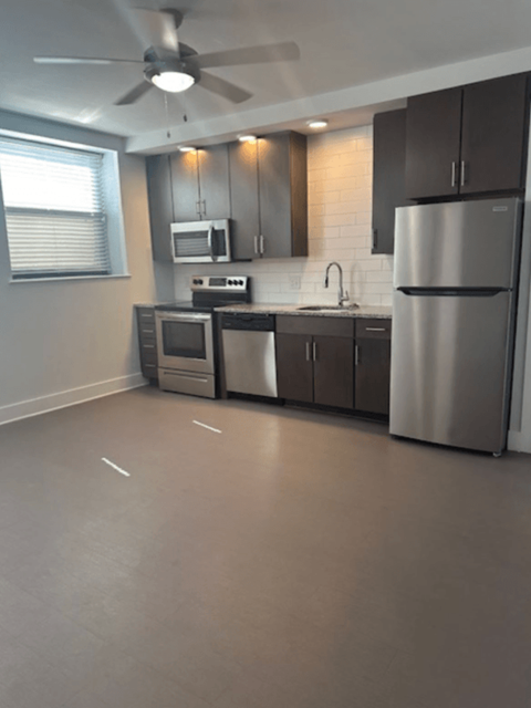 A modern kitchen with a refrigerator, microwave, and oven.