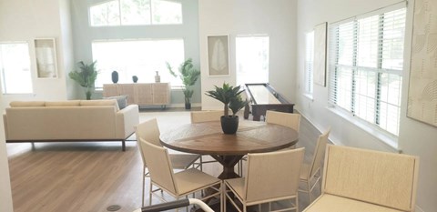 A living room with a brown table surrounded by beige chairs.