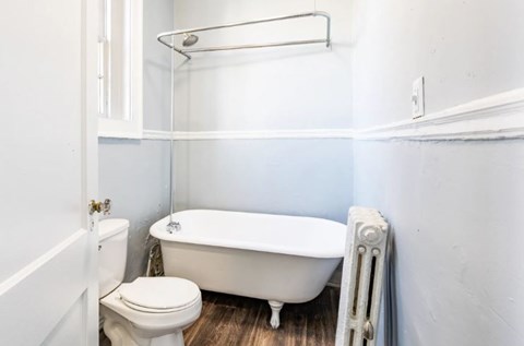 A white toilet sits next to a white bathtub in a bathroom.