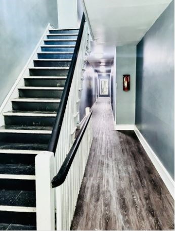 A staircase with a black handrail and wooden steps leading to a door.