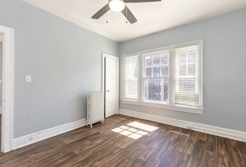 A room with a ceiling fan and a window with blinds.