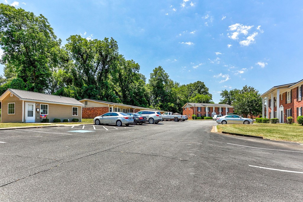 A parking lot with cars and residential buildings in the background.