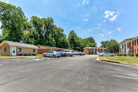 A parking lot with cars and residential buildings in the background.