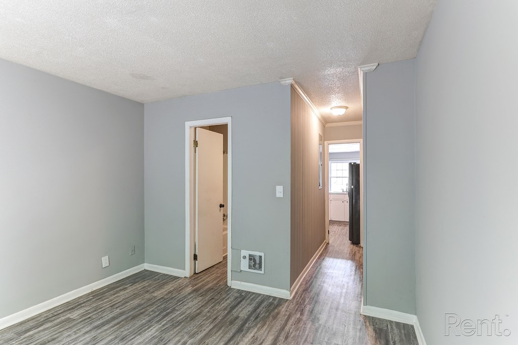 A room with a wooden floor and a doorway leading to another room.