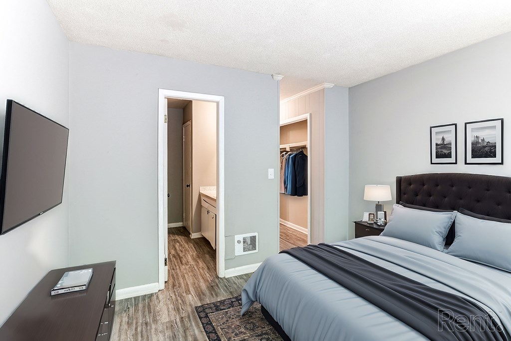 A bedroom with a bed and a flat screen TV mounted on the wall.