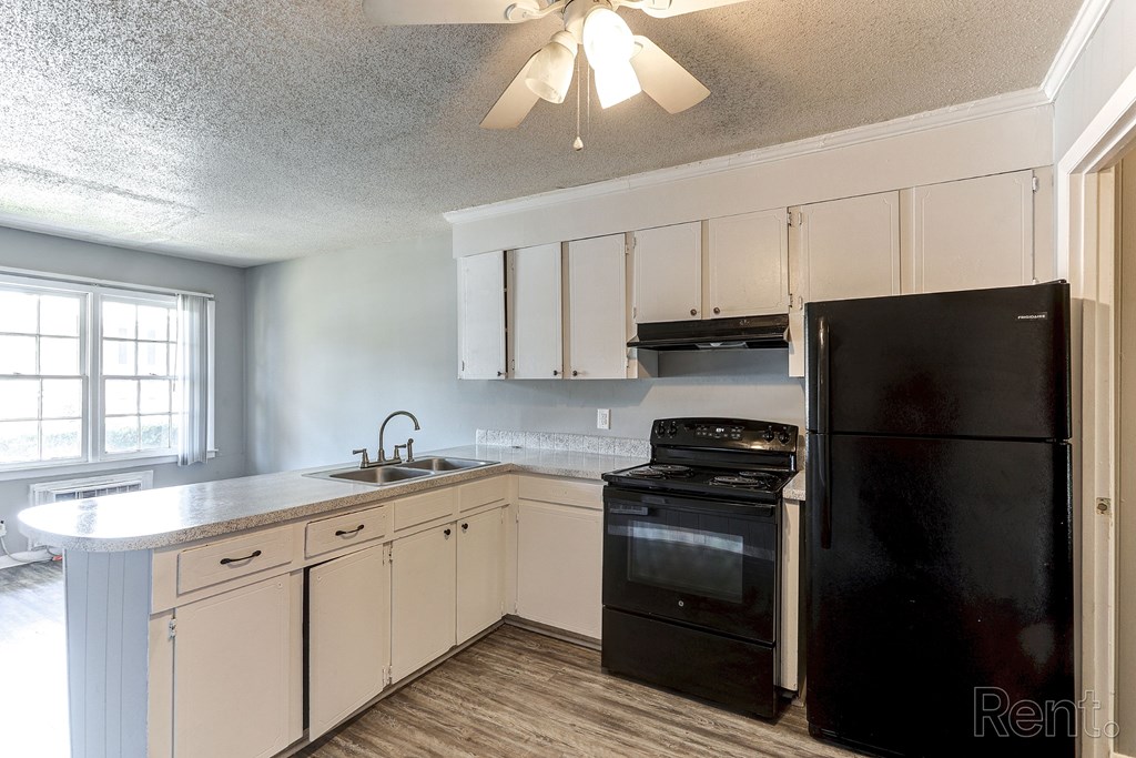 A kitchen with black appliances and white cabinets.