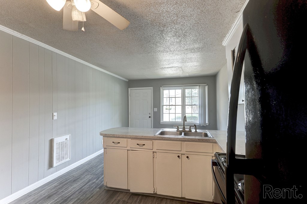 A kitchen with a sink and white cabinets.