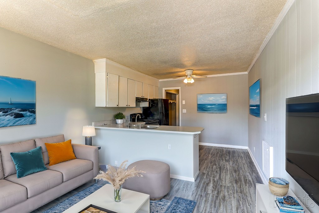 A living room with a couch, coffee table, a television, and a painting on the wall.