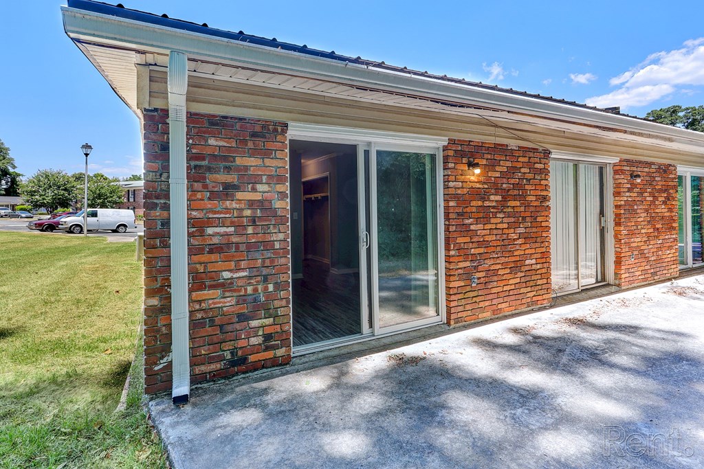 A red brick residential building with sliding glass doors leading out to a patio.