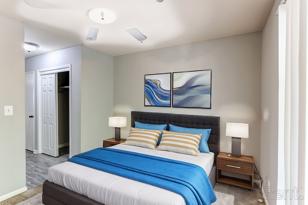 A bedroom with a bed, two lamps on nightstands, and a ceiling fan.