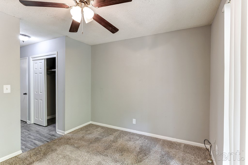 A room with a ceiling fan and a carpeted floor.
