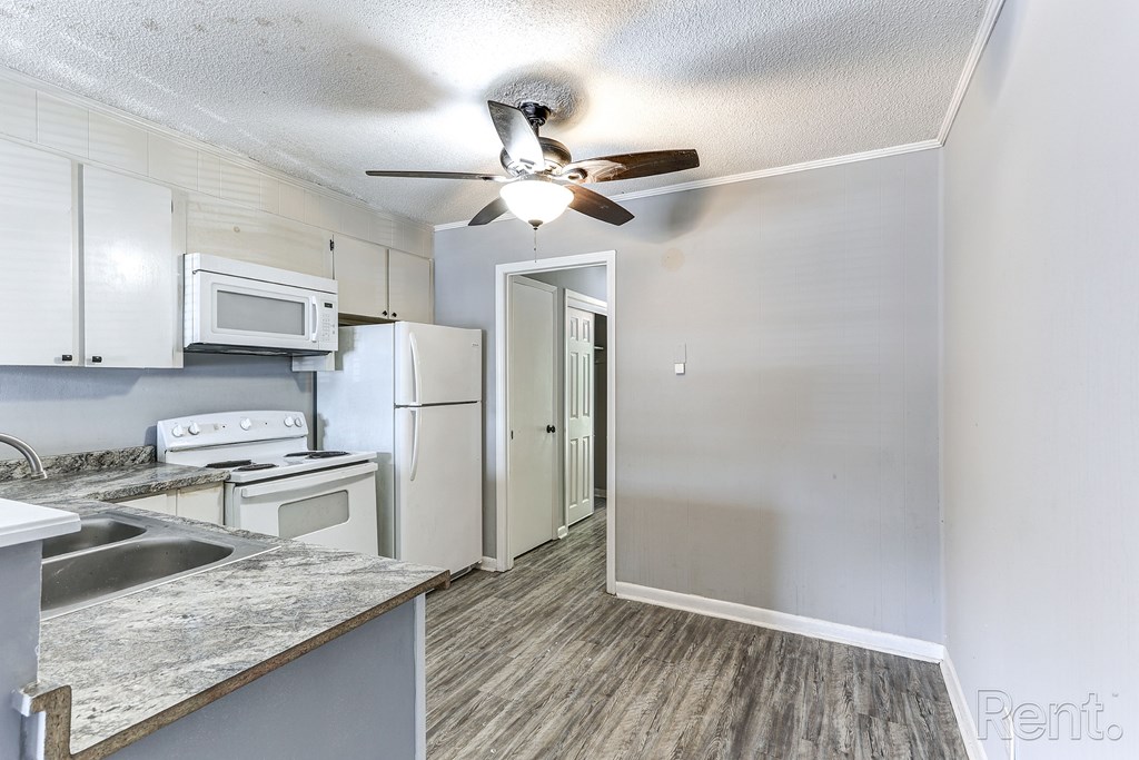 A kitchen with a refrigerator, microwave, and oven.