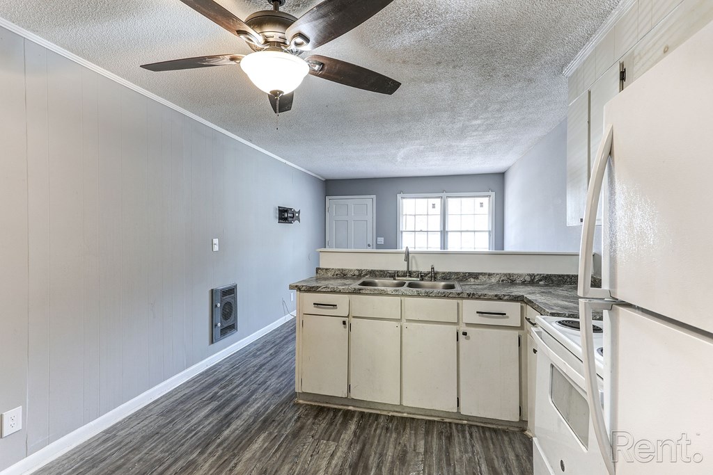 A kitchen with a ceiling fan and white cabinets.