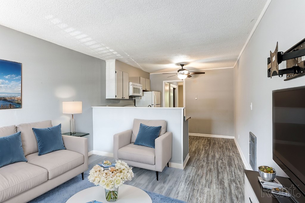 A living room with a couch, a chair, a television, and a coffee table with flowers on it.