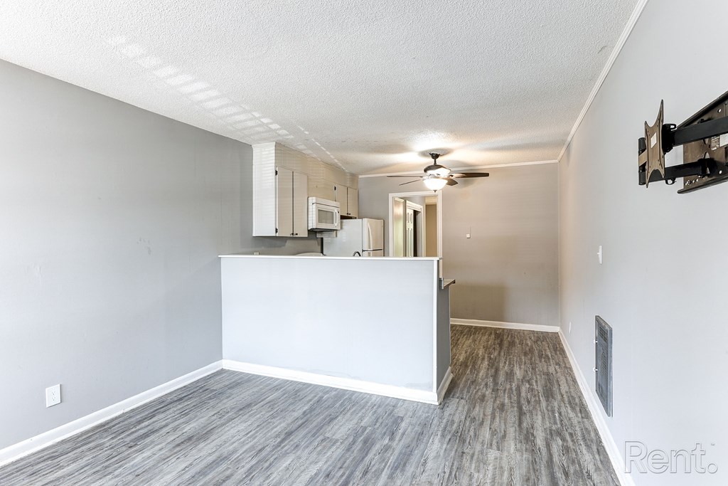 A room with a television mount and a ceiling fan.