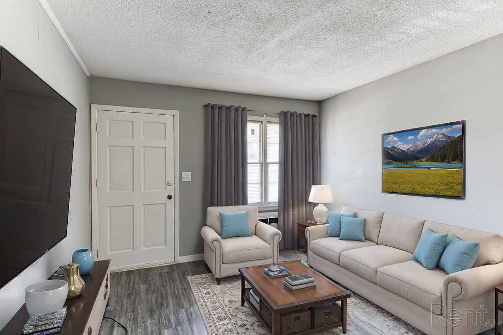 A living room with a couch, a chair, a coffee table, and a painting on the wall.