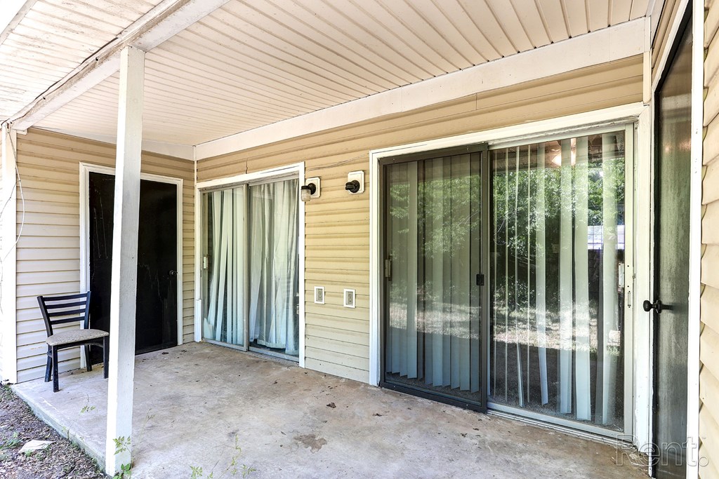 A patio with a chair and sliding glass doors.