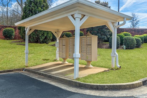 A small pavilion with a roof and a mailbox on the side.