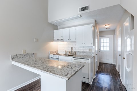 A kitchen with white cabinets and a granite countertop.
