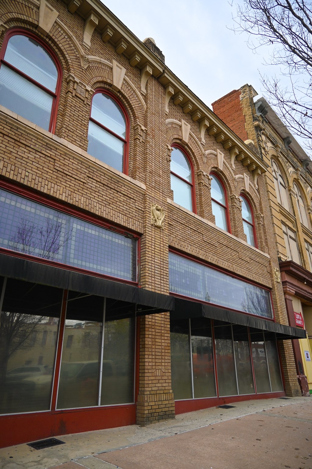 A red brick building with arched windows and a black awning.