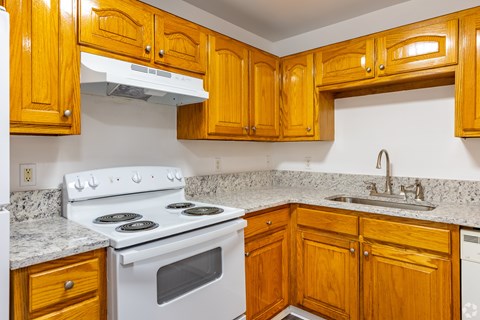 A kitchen with wooden cabinets and a white stove top oven.