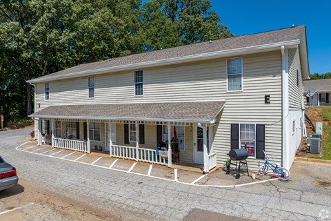 A white building with a porch and a bicycle parked in front.