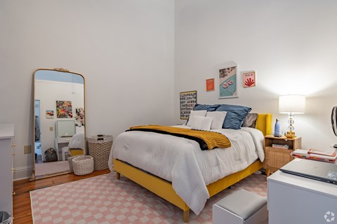 A bedroom with a bed, a mirror, and a desk.